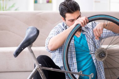Evde bisiklet tamir eden genç bir adam.