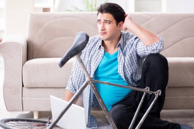 Evde bisiklet tamir eden genç bir adam.