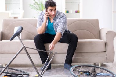 Evde bisiklet tamir eden genç bir adam.