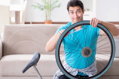 Evde bisiklet tamir eden genç bir adam.