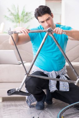 Evde bisiklet tamir eden genç bir adam.