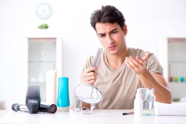 Genç yakışıklı adam aynaya bakıyor. 