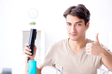 Genç yakışıklı adam aynaya bakıyor. 