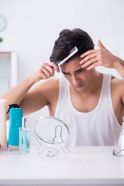 Genç yakışıklı adam aynaya bakıyor. 