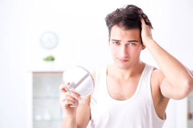 Genç yakışıklı adam aynaya bakıyor. 