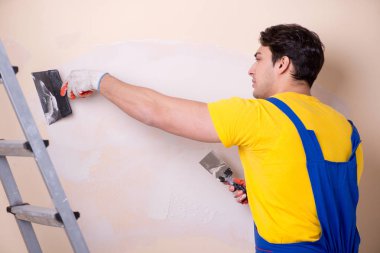 Duvara alçı yapıştıran genç müteahhit.