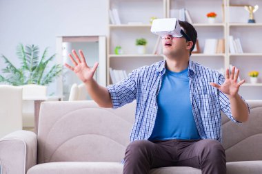 Evde sanal gerçeklik gözlüklü bir adam oynuyor.