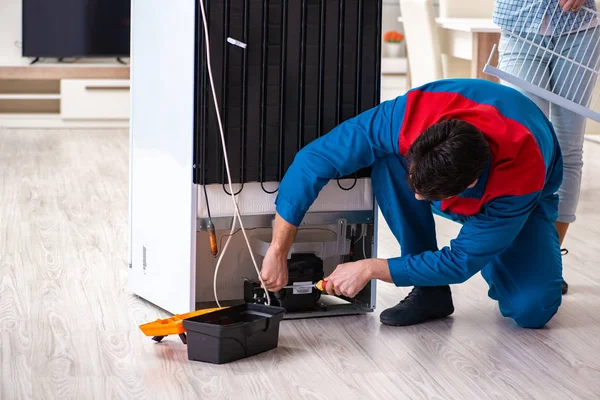 Man repairing fridge with customer