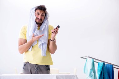 Yakışıklı koca evde kıyafet ütülüyor.