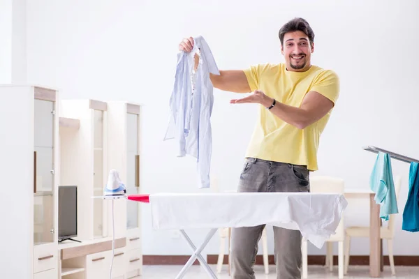 Bonito homem marido fazendo roupas de engomar em casa — Fotografia de Stock