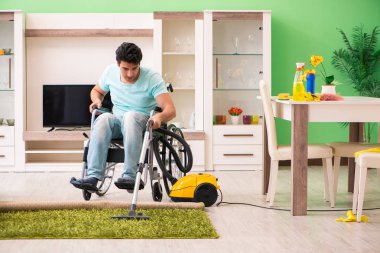 Tekerlekli sandalyedeki engelli adam elektrikli süpürge evi.