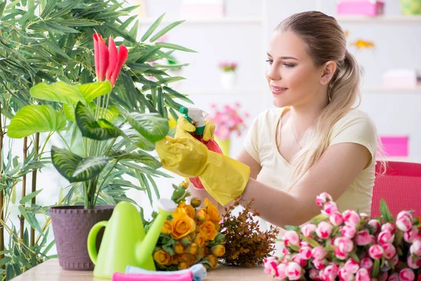 Молода жінка поливає рослини в саду — стокове фото