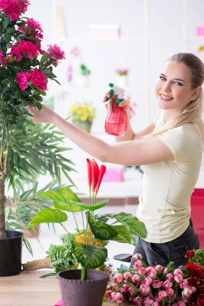 Молодая женщина поливает растения в своем саду — стоковое фото