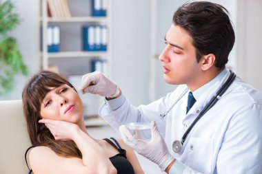 Doktor muayene sırasında hastaların kulaklarını kontrol ediyor.