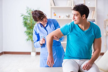 Doktor çekiçle sinir reflekslerini kontrol ediyor