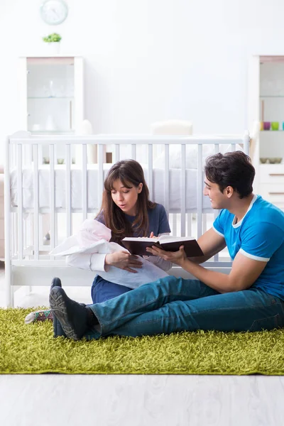 Młodzi rodzice z noworodkiem siedzącym na dywanie — Zdjęcie stockowe