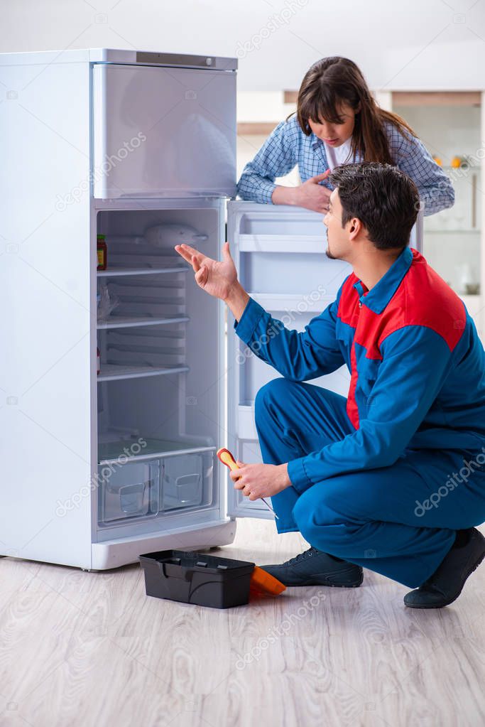 Man repairing fridge with customer