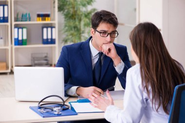 İş adamı doktorla sağlık sorunlarını tartışıyor