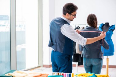 Profesyonel terzi resmi kıyafet için ölçü alıyor.