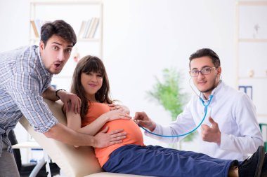 Hamile kadın kocasıyla klinikteki doktoru ziyaret ediyor.