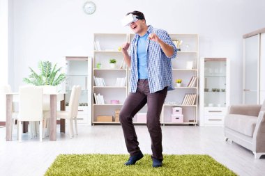 Evde sanal gerçeklik gözlüklü bir adam oynuyor.