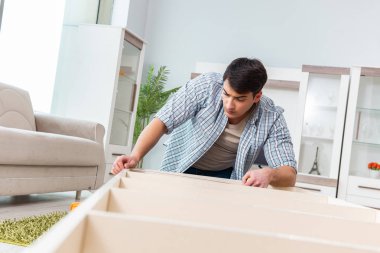 Adam evde mobilya montajı yapıyor.