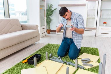 Adam evde mobilya montajı yapıyor.