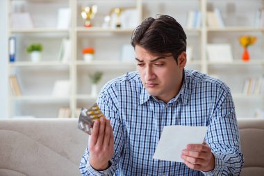 Kanepede ilaç ve reçeteyle oturan genç adam. 