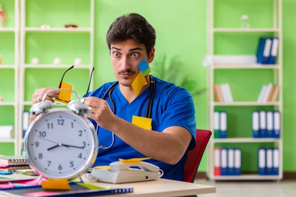 Hastanede oturan genç doktor, birçok çelişkili önceliğe sahip. — Stok fotoğraf