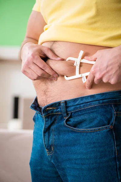 Giovane uomo misurare il grasso corporeo con pinze — Foto Stock