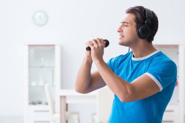 Genç yakışıklı adam evde karaoke yapıyor. 