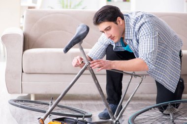 Evde bisiklet tamir eden genç bir adam.