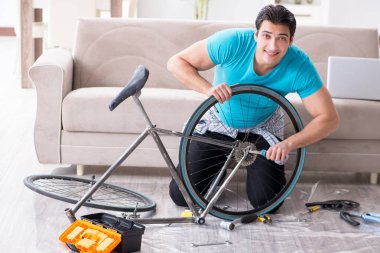 Evde bisiklet tamir eden genç bir adam.