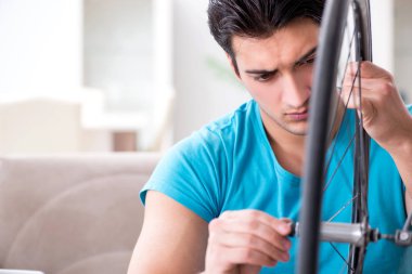 Evde bisiklet tamir eden genç bir adam.