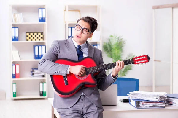 Joven hombre de negocios guapo tocando la guitarra en la oficina — Foto de Stock