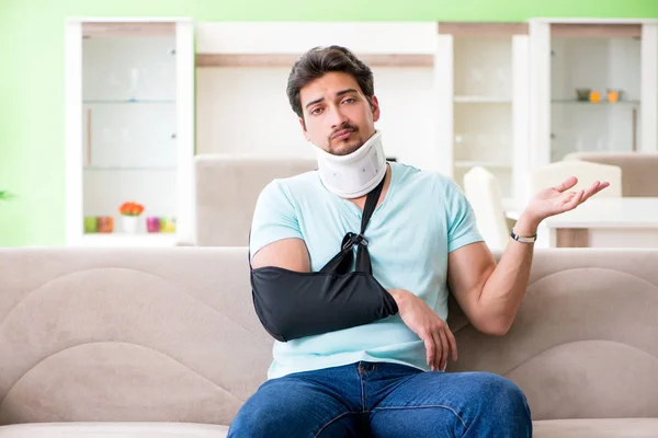 Young student man with neck and hand injury sitting on the sofa