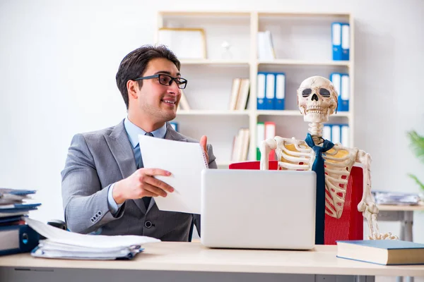Empresario trabajando con el esqueleto en la oficina —  Fotos de Stock