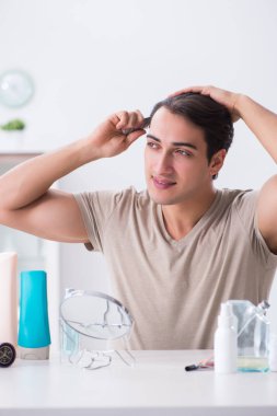 Genç yakışıklı adam aynaya bakıyor. 