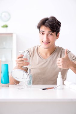 Genç yakışıklı adam aynaya bakıyor. 