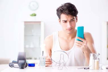 Genç yakışıklı adam aynaya bakıyor. 