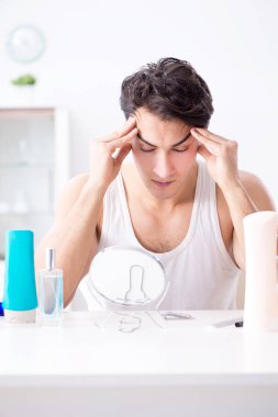 Genç yakışıklı adam aynaya bakıyor. 