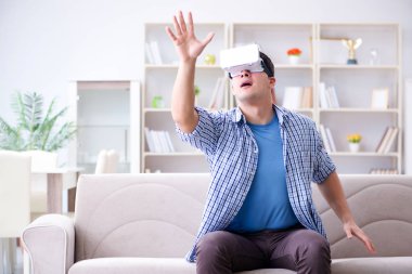 Evde sanal gerçeklik gözlüklü bir adam oynuyor.