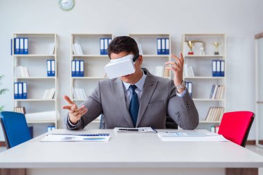 Ofiste sanal gerçeklik gözlüklü bir iş adamı var.