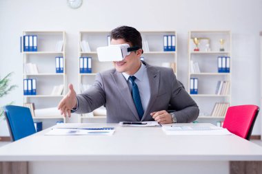 Ofiste sanal gerçeklik gözlüklü bir iş adamı var.