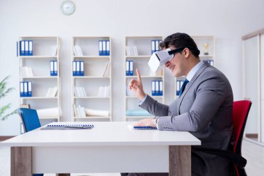 Ofiste sanal gerçeklik gözlüklü bir iş adamı var.