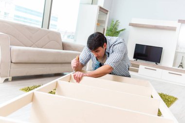 Adam evde mobilya montajı yapıyor.