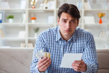 Kanepede ilaç ve reçeteyle oturan genç adam. 