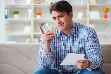 Kanepede ilaç ve reçeteyle oturan genç adam. 