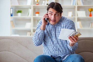 Kanepede ilaç ve reçeteyle oturan genç adam. 