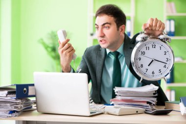 Ofiste otururken aşırı çalışmaktan kızgın bir iş adamı.